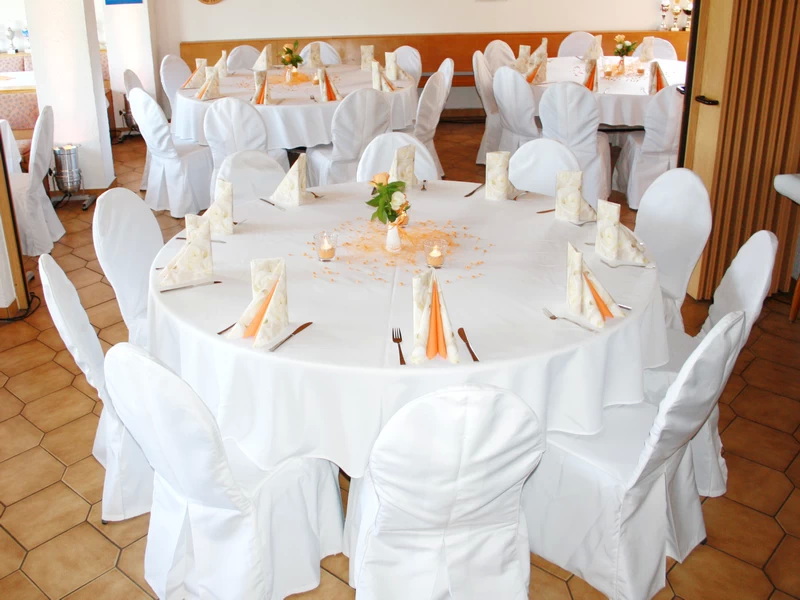 Stühle mit Stuhlhussen und runden Tischen auf Hochzeit